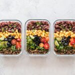 Healthy meal prep containers with grains, vegetables and lentils