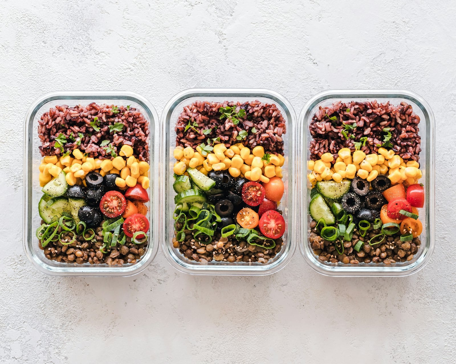 Healthy meal prep containers with grains, vegetables and lentils