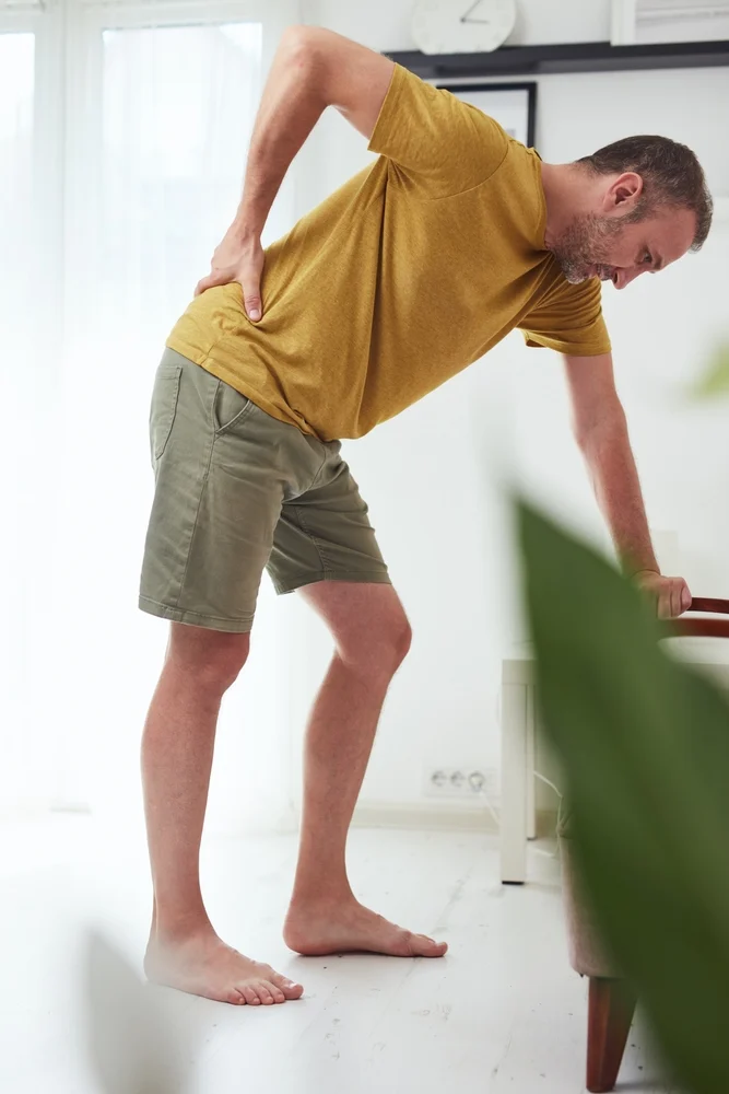 Man holding his lower back in pain, representing chronic pain treated with lidocaine infusion in San Marcos